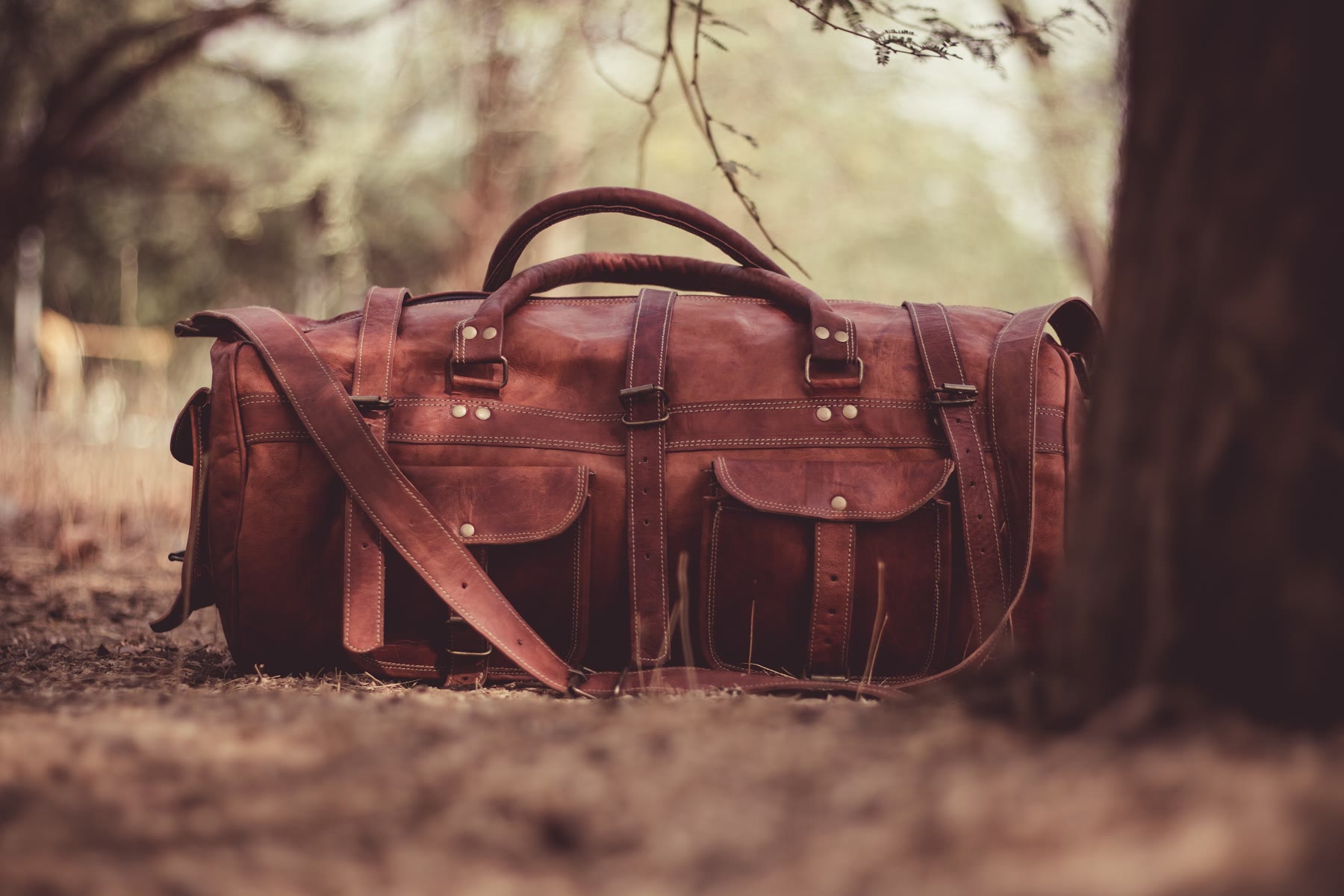 Bolsa de viagem de couro marrom com alças e bolsos de fivela